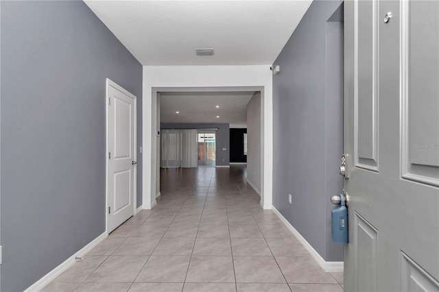 hall with light tile patterned floors, baseboards, visible vents, and a barn door