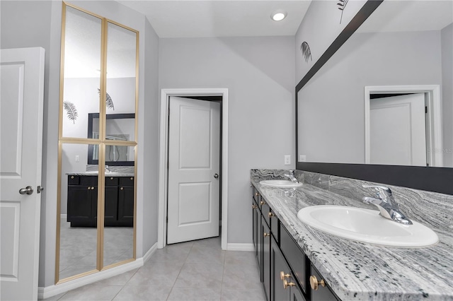 bathroom featuring double vanity, tile patterned flooring, a sink, and baseboards