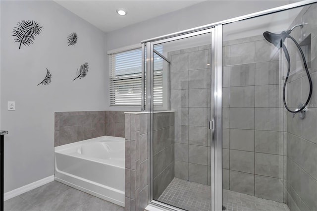 bathroom featuring a garden tub, a shower stall, baseboards, and tile patterned floors