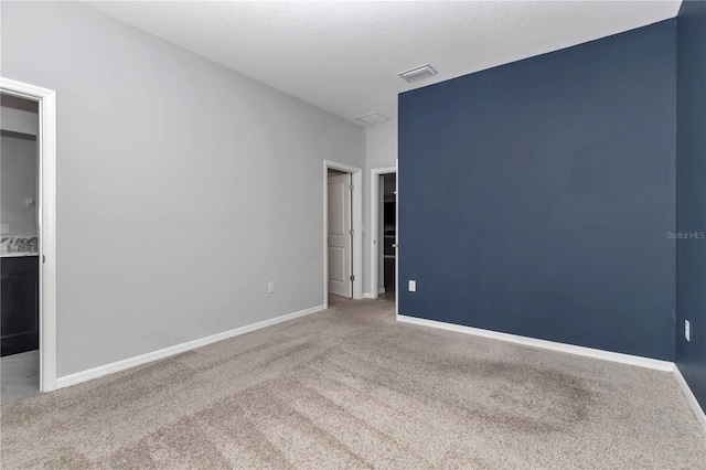 carpeted spare room with visible vents, a textured ceiling, and baseboards