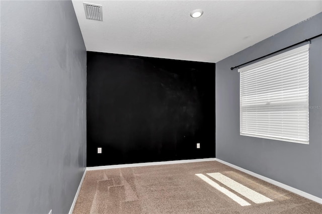 unfurnished room with carpet, visible vents, and baseboards