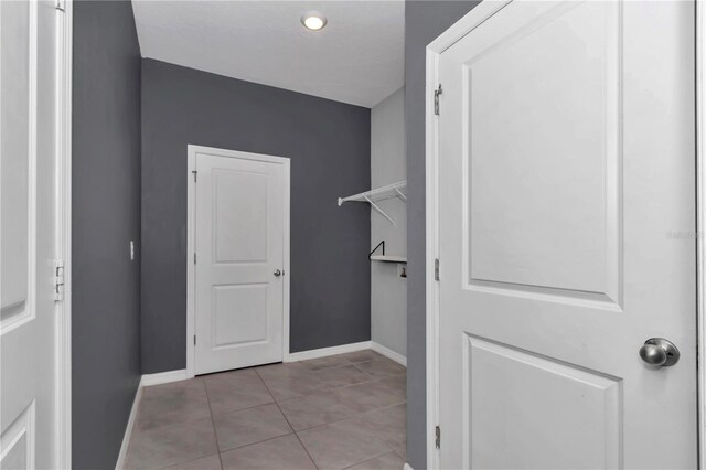 hallway featuring light tile patterned floors and baseboards