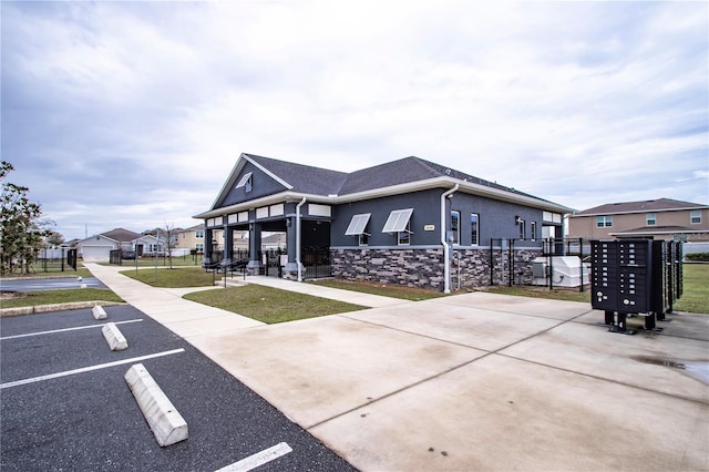 exterior space featuring fence, a residential view, stucco siding, uncovered parking, and a front lawn