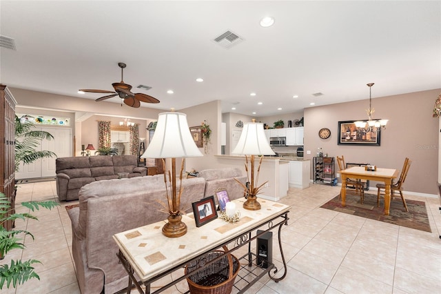 living area featuring ceiling fan with notable chandelier, recessed lighting, visible vents, and light tile patterned floors