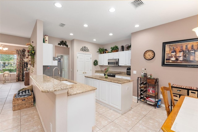 kitchen featuring a peninsula, stainless steel microwave, a sink, and visible vents