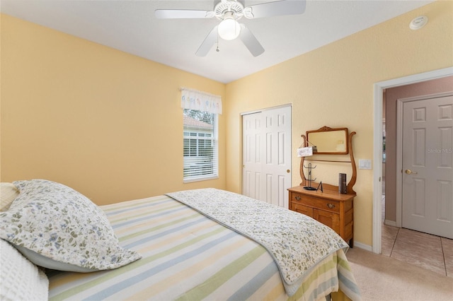 bedroom with baseboards, a closet, a ceiling fan, and light colored carpet