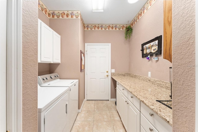 clothes washing area with light tile patterned floors, laundry area, washing machine and dryer, and baseboards