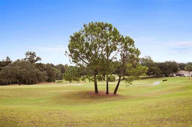 view of home's community with view of golf course and a lawn