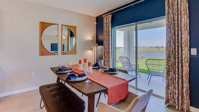 dining room with a water view, tile patterned flooring, and baseboards