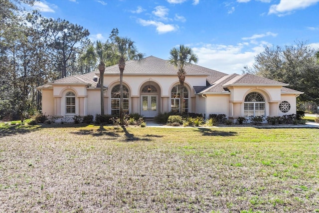 mediterranean / spanish home with roof with shingles, french doors, a front lawn, and stucco siding