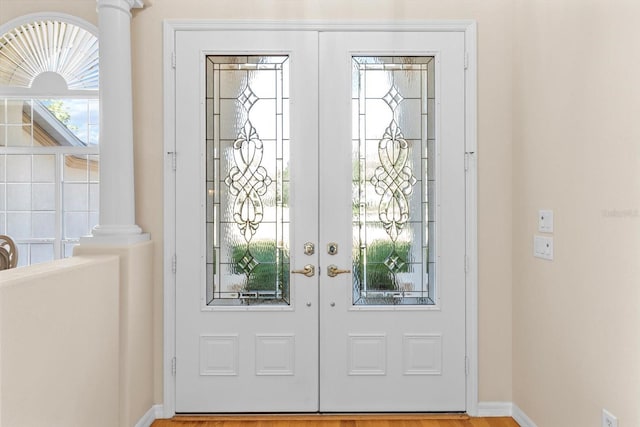 foyer entrance with baseboards, french doors, and ornate columns