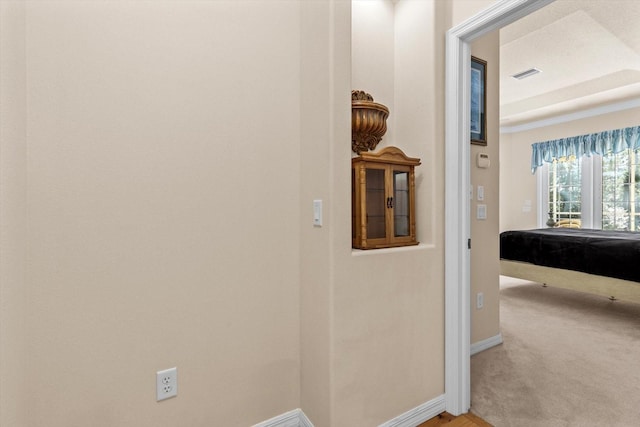 hallway featuring carpet floors, visible vents, and baseboards