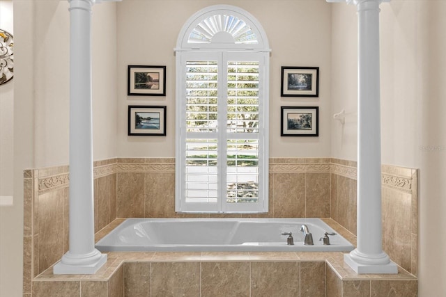 bathroom with ornate columns and a bath