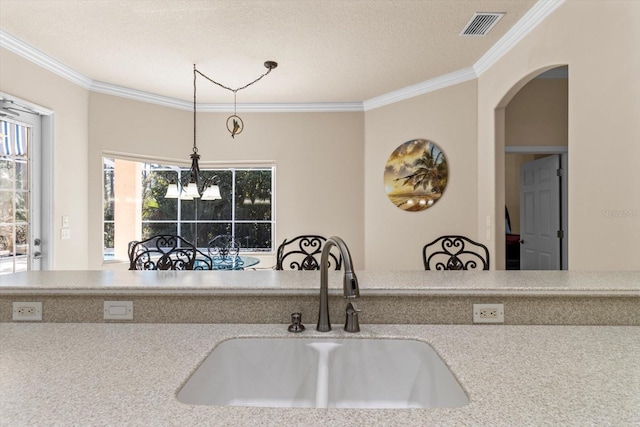 kitchen featuring visible vents, ornamental molding, decorative light fixtures, a chandelier, and a sink