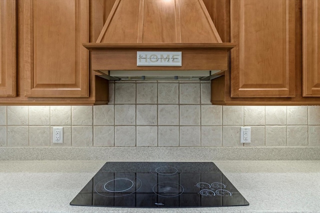 kitchen with light countertops, custom range hood, backsplash, and black electric cooktop