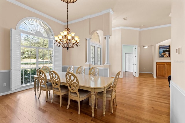 dining area with ornate columns, ornamental molding, and light wood-style floors