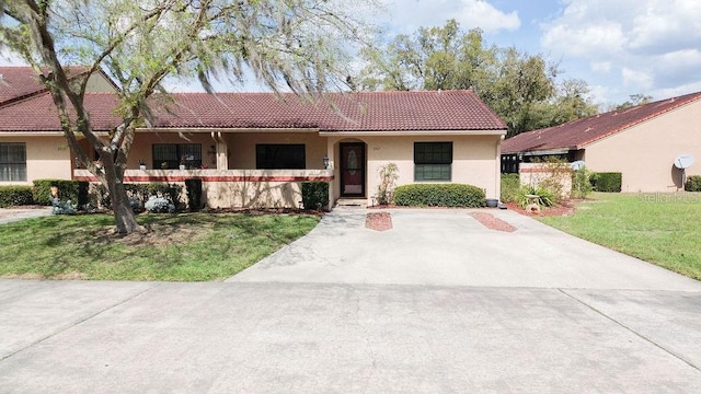 ranch-style house with stucco siding, a front yard, and a tiled roof