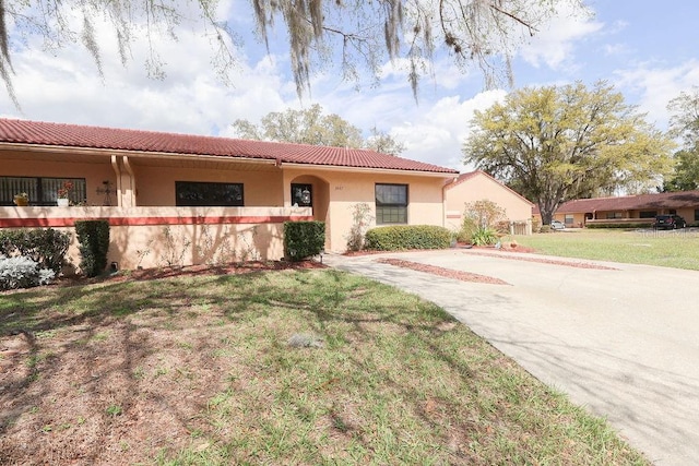 3447 SW 19th Pl, Ocala, FL 34474 - view of front of property with a tiled roof, stucco siding, and a front lawn