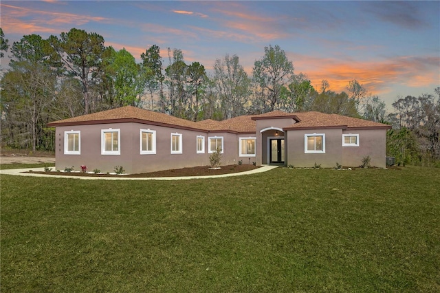 mediterranean / spanish-style home featuring a yard and stucco siding