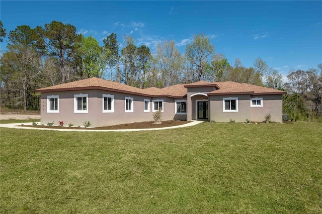 rear view of property featuring stucco siding and a yard