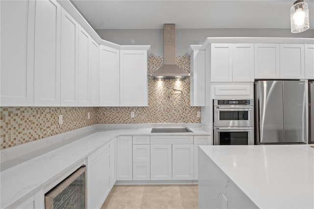 kitchen with stainless steel appliances, backsplash, white cabinetry, beverage cooler, and wall chimney exhaust hood