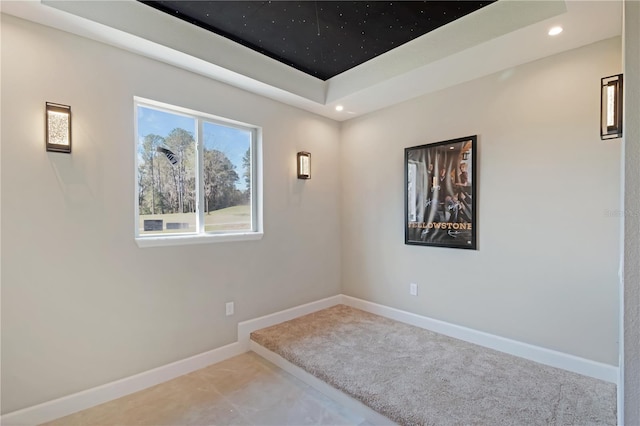 empty room with recessed lighting, a raised ceiling, carpet flooring, and baseboards