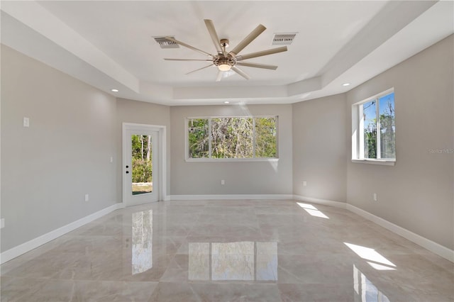 spare room with baseboards, visible vents, a tray ceiling, and recessed lighting