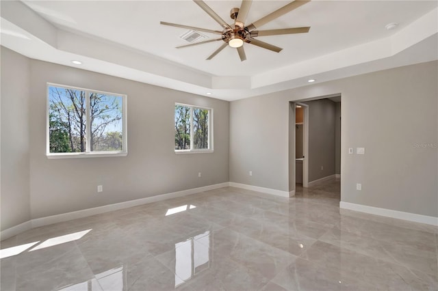 spare room featuring a tray ceiling, recessed lighting, visible vents, a ceiling fan, and baseboards