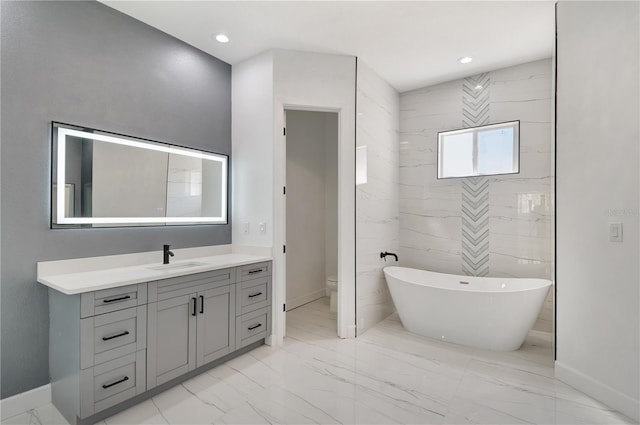 bathroom with toilet, marble finish floor, a freestanding bath, vanity, and recessed lighting