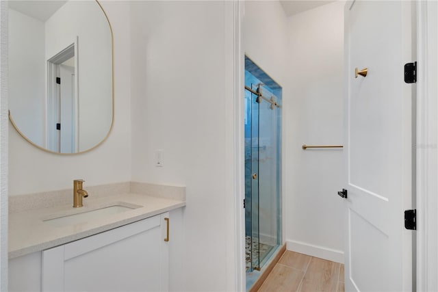 full bathroom featuring a shower stall, baseboards, wood finished floors, and vanity