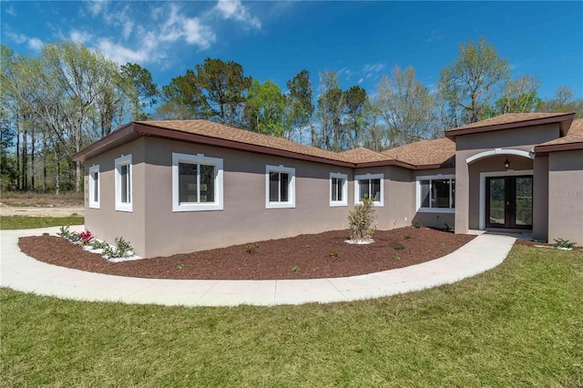 view of property exterior featuring a yard, french doors, and stucco siding