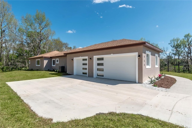 view of front of house featuring a garage, a front yard, central air condition unit, and stucco siding