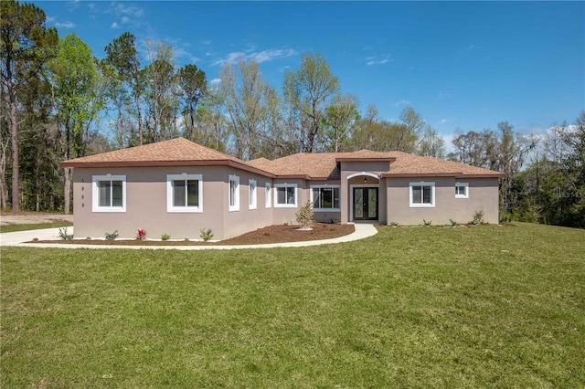 rear view of house with stucco siding, french doors, and a yard