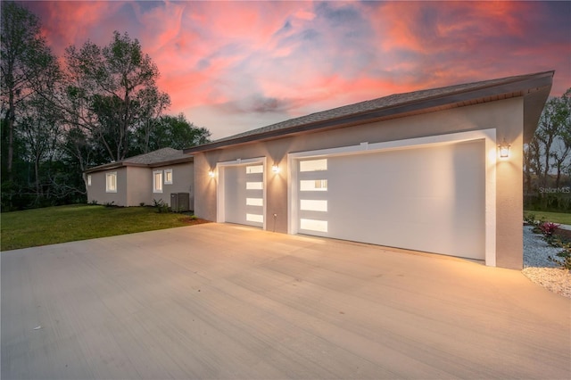 view of front of house with a garage, concrete driveway, a lawn, and stucco siding