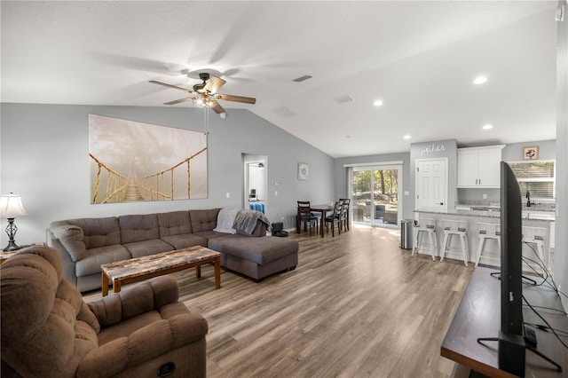 living room with visible vents, lofted ceiling, ceiling fan, light wood-style floors, and recessed lighting