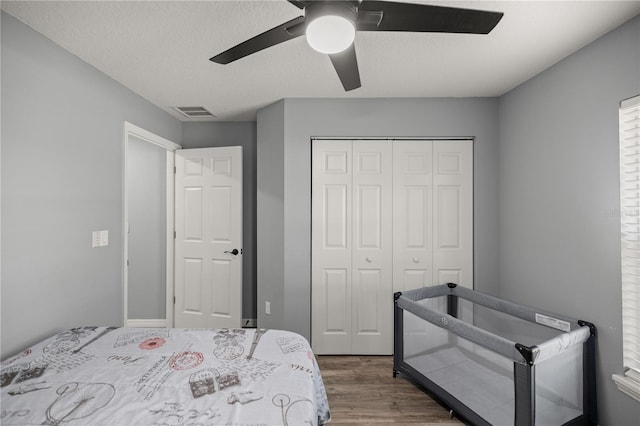 bedroom featuring visible vents, ceiling fan, wood finished floors, a textured ceiling, and a closet