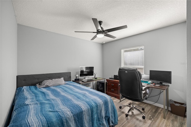 bedroom featuring a textured ceiling, ceiling fan, light wood-type flooring, and baseboards