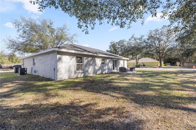 view of side of property featuring cooling unit, a lawn, and stucco siding