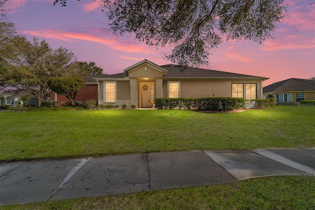 single story home featuring a lawn and stucco siding