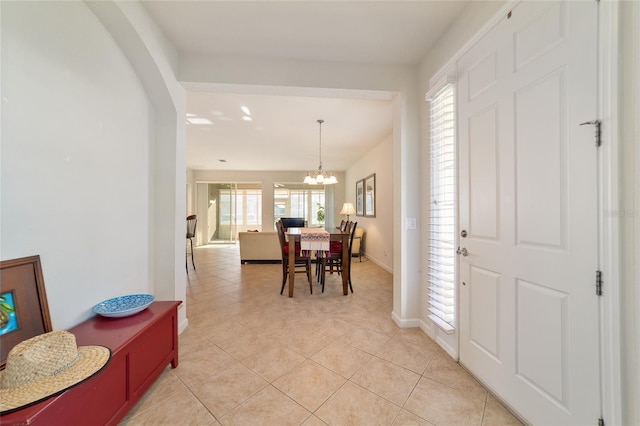 entryway featuring baseboards, light tile patterned flooring, and an inviting chandelier