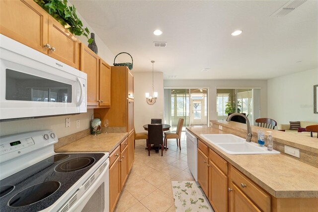 kitchen featuring white appliances, a notable chandelier, light countertops, and a sink