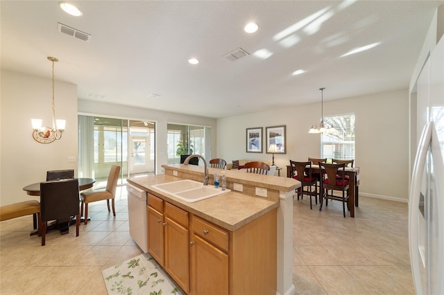 kitchen featuring white appliances, visible vents, an inviting chandelier, light countertops, and a sink