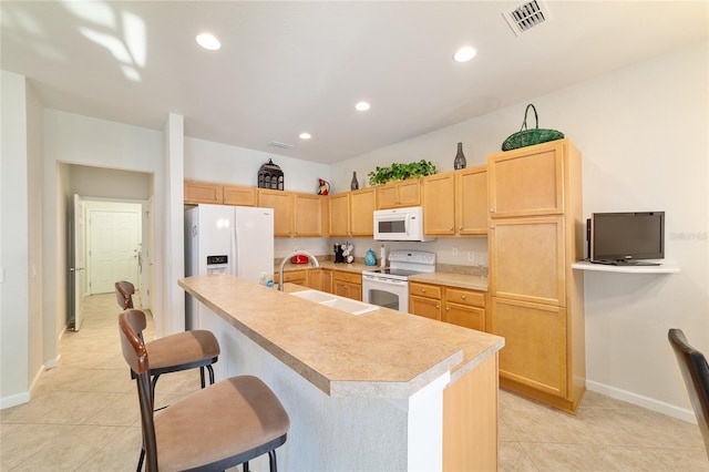 kitchen featuring a breakfast bar area, light countertops, visible vents, a sink, and white appliances