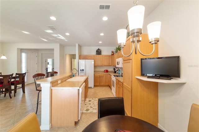 kitchen featuring white appliances, a breakfast bar area, a kitchen island with sink, light countertops, and a sink