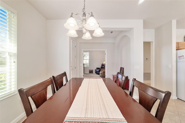 dining space with light tile patterned flooring, a notable chandelier, and baseboards