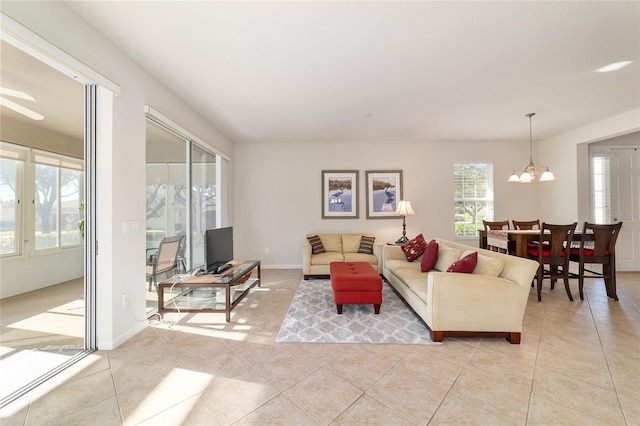 living area featuring baseboards, a notable chandelier, and light tile patterned flooring