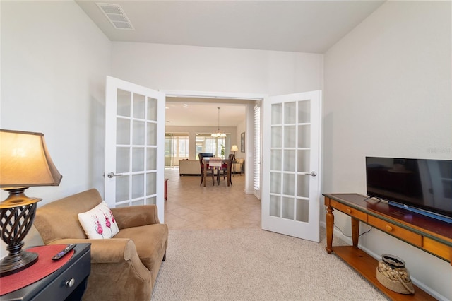 living area featuring french doors, visible vents, carpet flooring, and an inviting chandelier