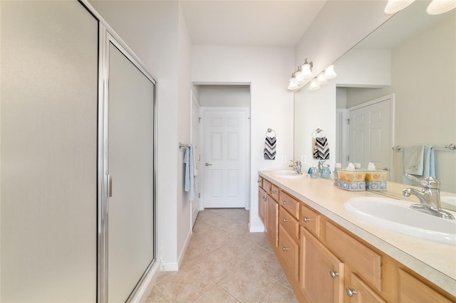 bathroom with double vanity, a stall shower, baseboards, tile patterned flooring, and a sink