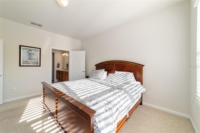 carpeted bedroom with connected bathroom, visible vents, and baseboards