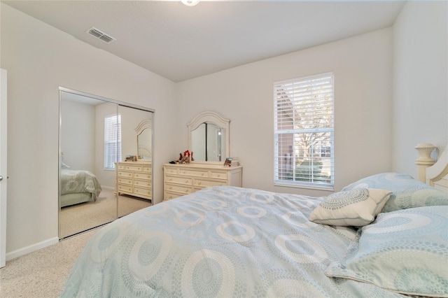 carpeted bedroom with baseboards, visible vents, and a closet